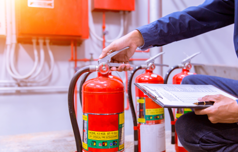 Hand eines Mannes am Griff eines Feuerlöschers